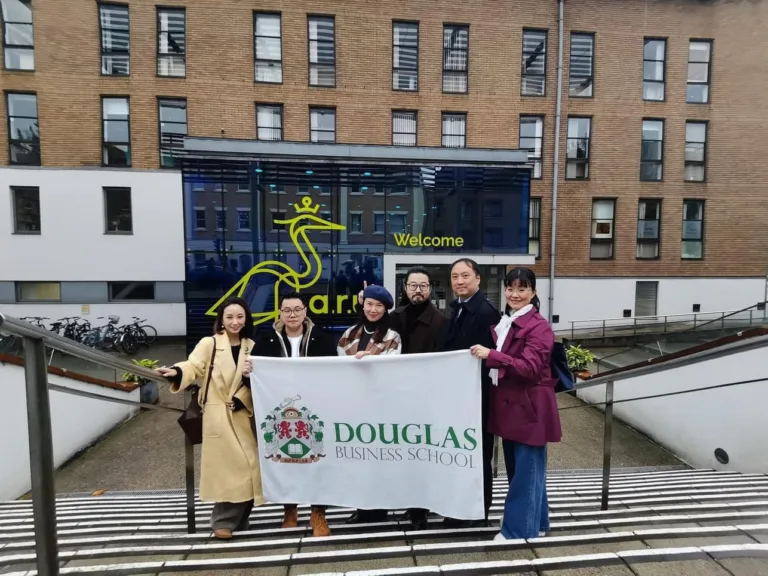 graduated student from douglas business school standing in front of Anglia Ruskin University